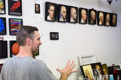 Artist Brent Holland with collection of self-portraits