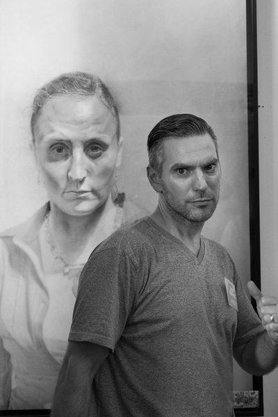Artist Brent Holland in front of a drawing he made of his wife, Erica